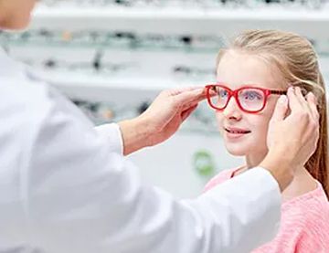 optician putting glasses on a child