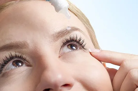 woman putting eye drops in her eye