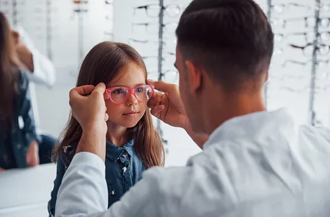 optician putting glasses on a child