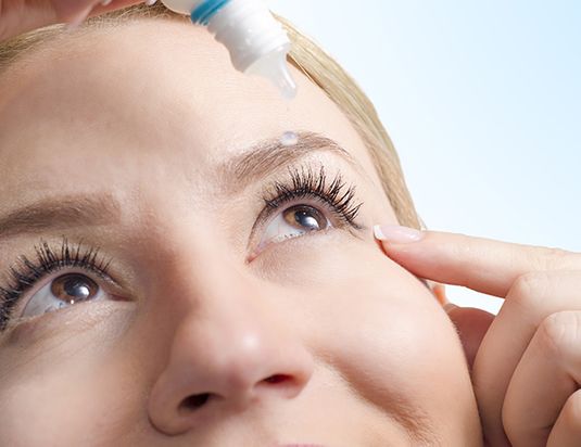 woman putting eye drops in her eye